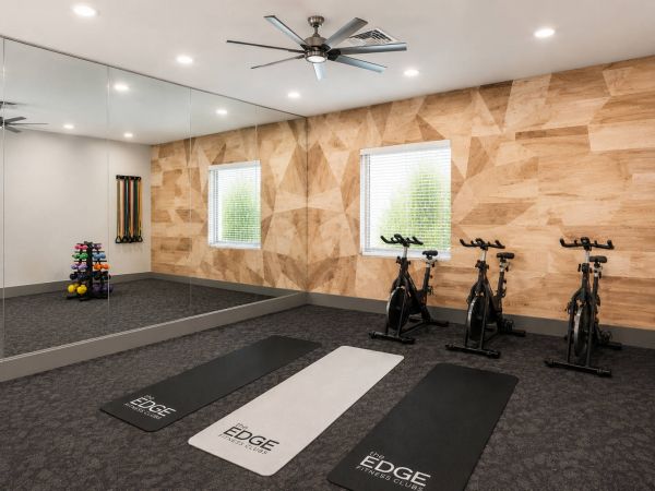 Spin and stretch studio with stationary bikes, yoga mats, resistance bands, mirrors, and branded The Edge fitness mats.
